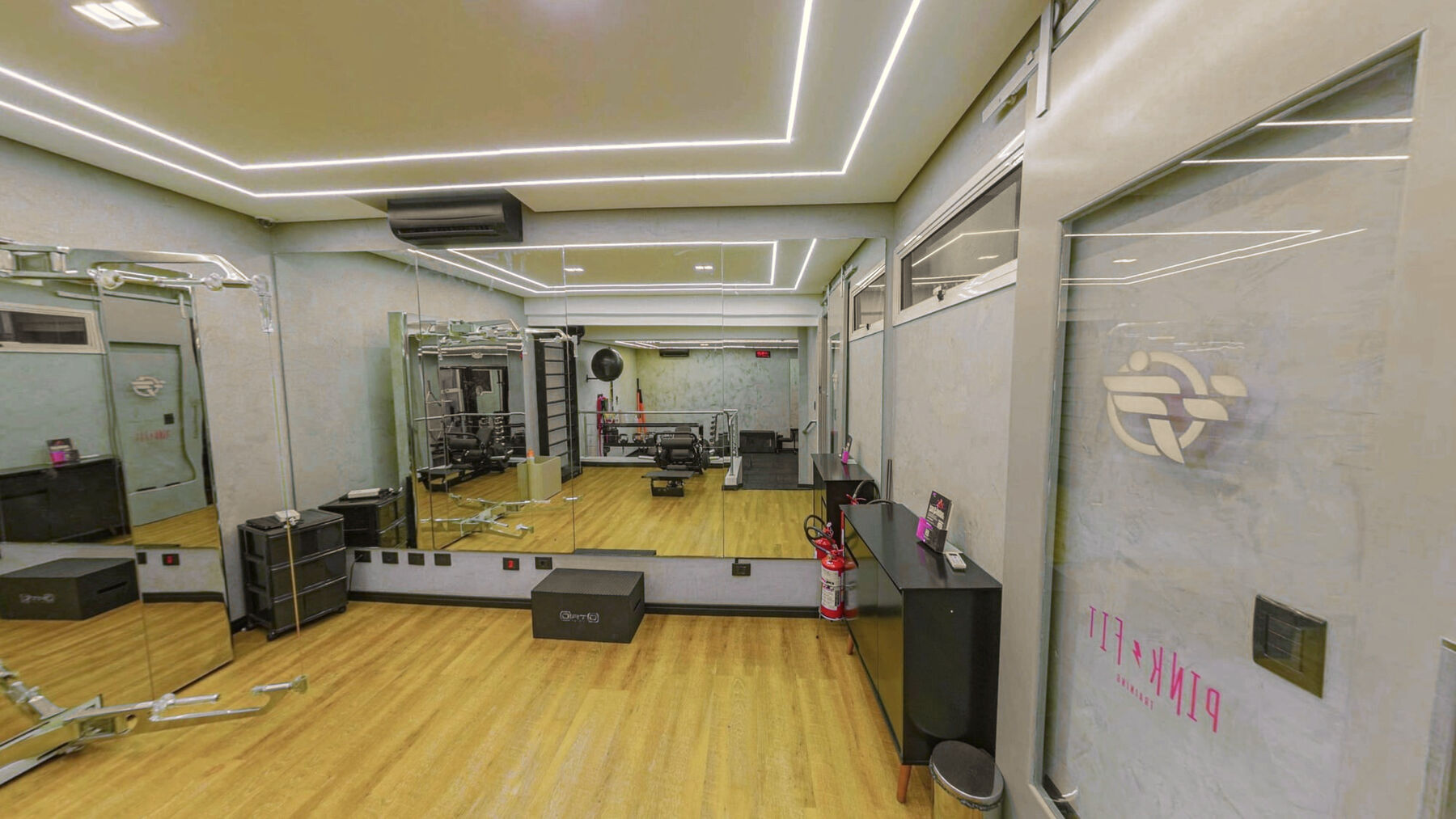 Espaço de treino com piso de madeira, espelho e a marca na parede