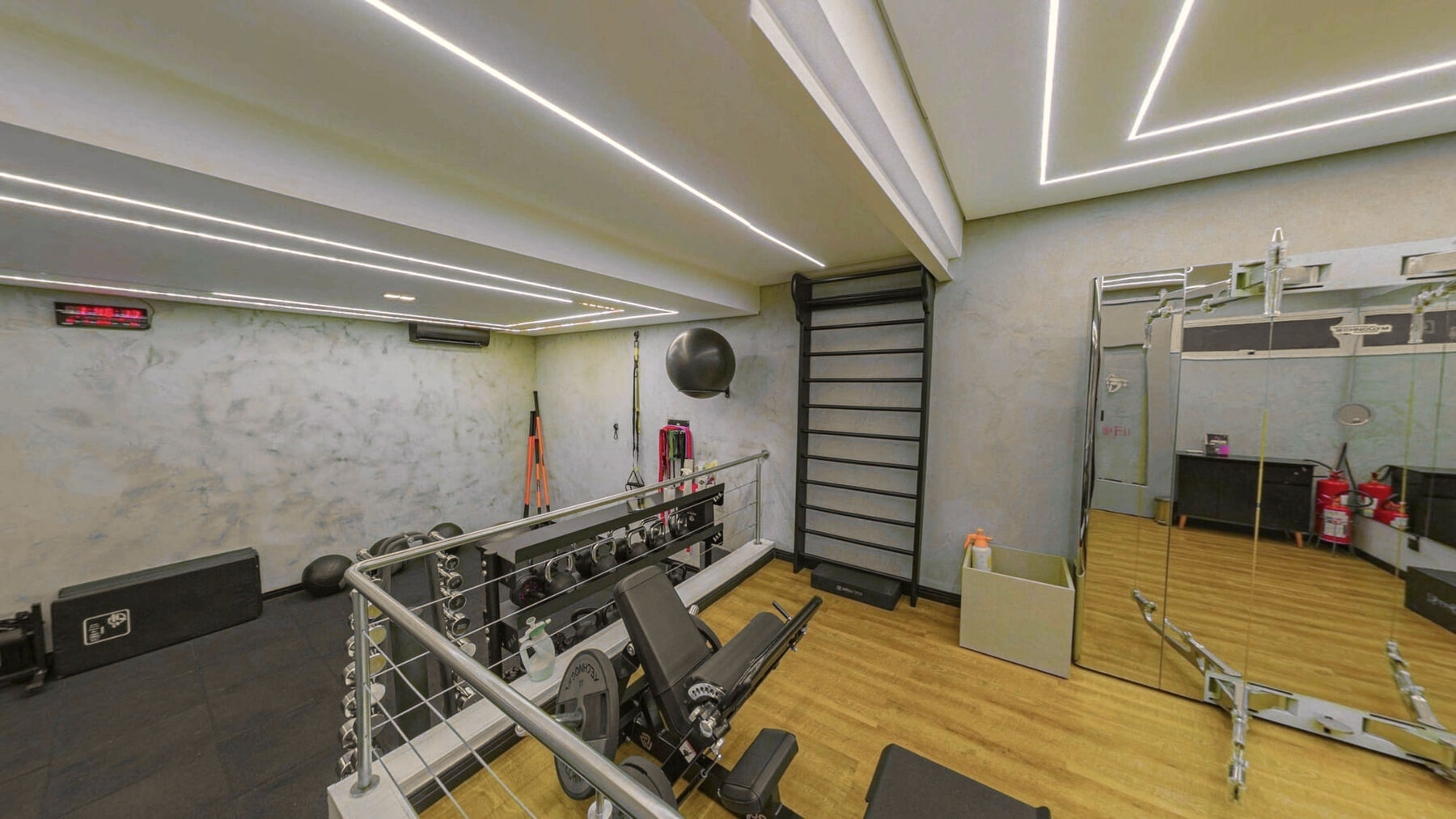 Área de funcional do studio, com espaldar, halteres e piso de madeira