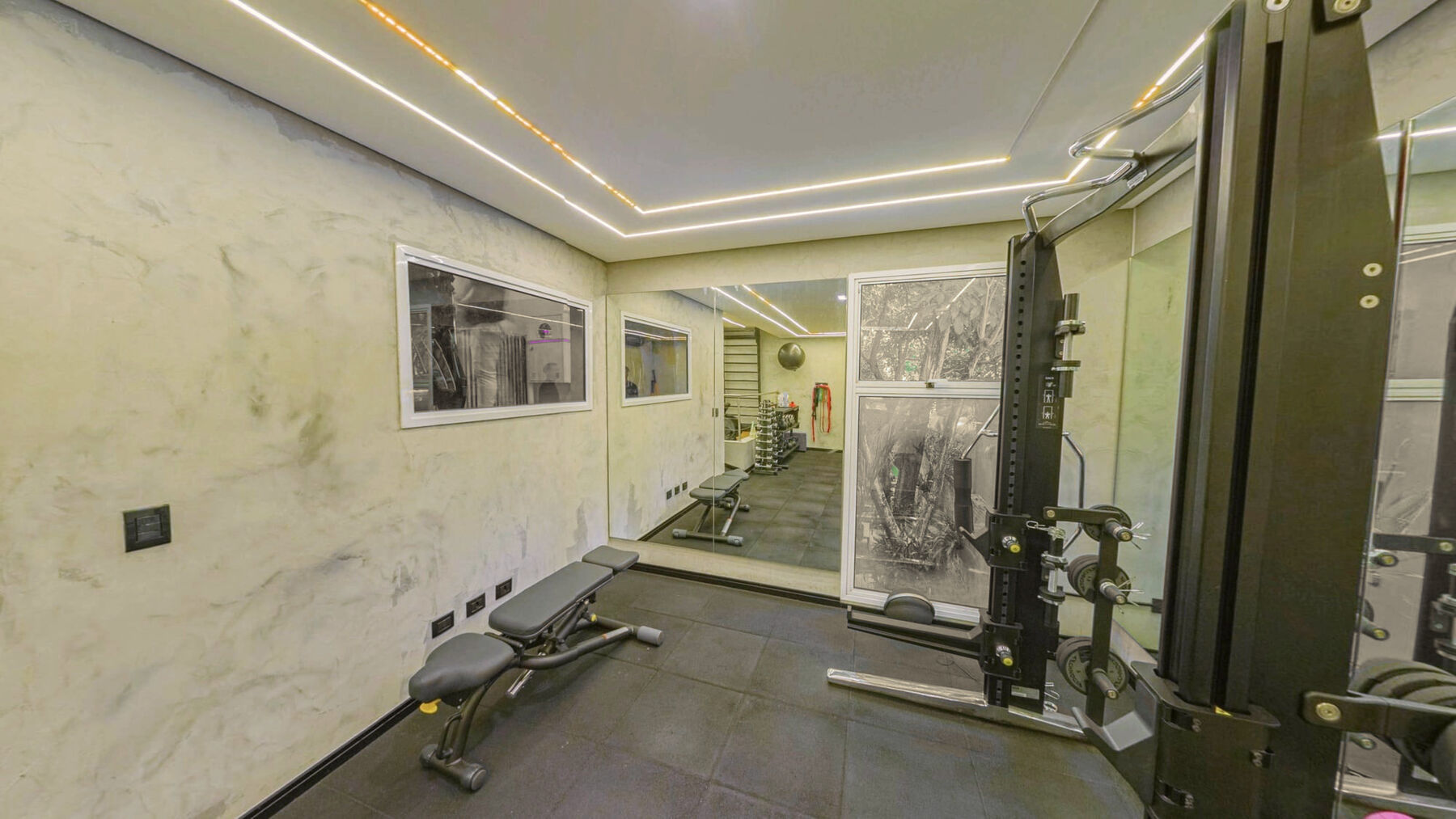 Sala de treino com rack, banco e a janela para o jardim